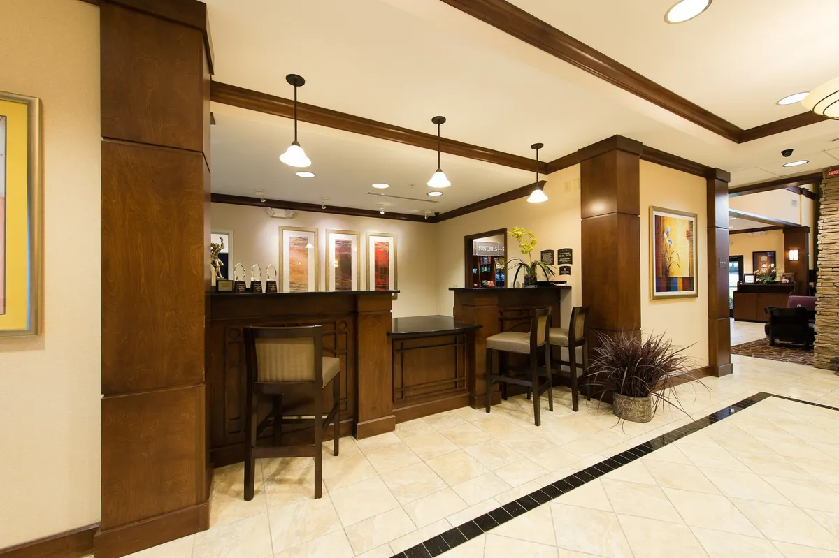 An interior scene showing the reception desk, artwork, and a comfortable seating area, where guests are greeted and relax before heading out. The overall ambiance is inviting, with subtle cues of professionalism and comfort.